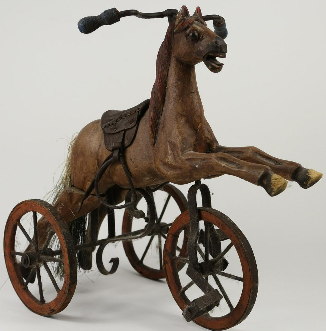 VINTAGE WOODEN TRICYCLE HORSE TOY: Vintage carved wood and cast iron tricycle horse toy. Measures 14" length x 13 1/2" height.
