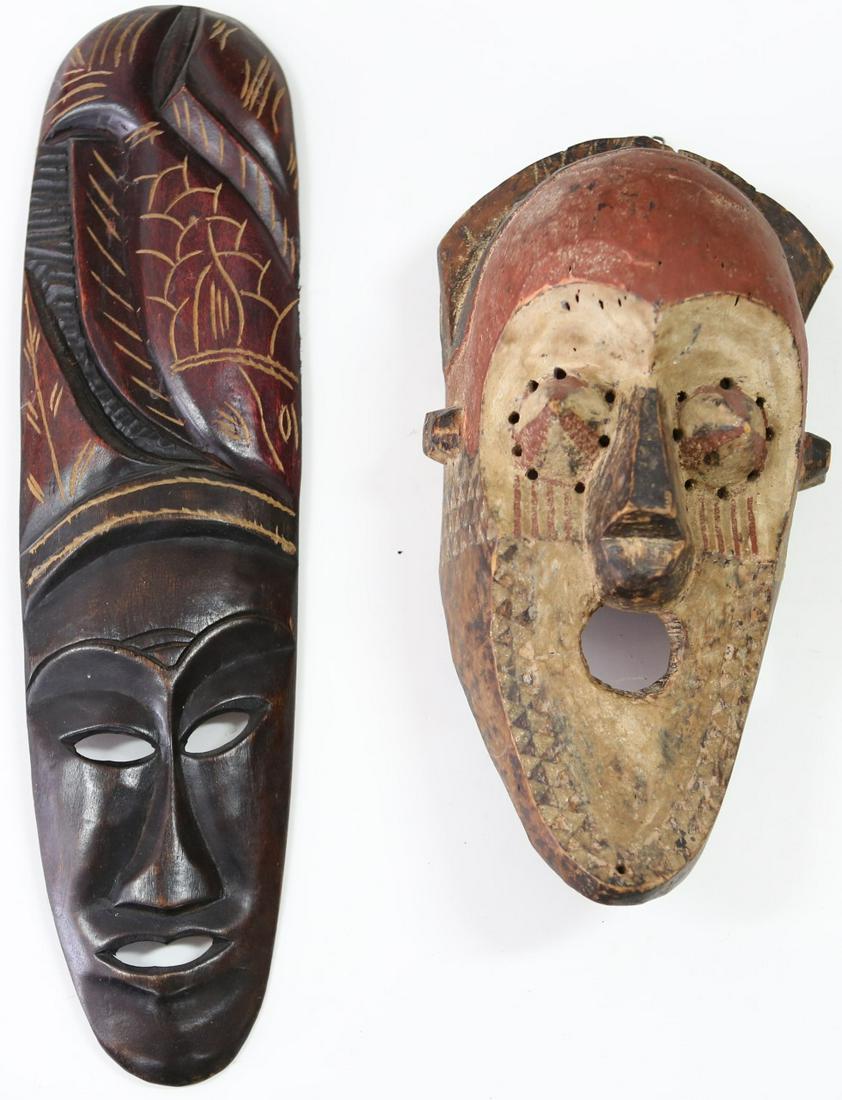 2pc TRIBAL CARVED WOOD MASKS: Two tribal carved wood masks. Longer mask with fish headdress-23 1/2". Second mask with cone-shaped eyes and decorated with geometric pattern-16 3/4".
