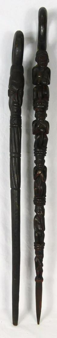 2pc AFRICAN TRIBAL CARVED WOOD CANES: Two African tribal wooden walking sticks with ring handles. One decorated with figures measures 43 3/4". One decorated with masks and geometric decoration measures 40 3/4" length.