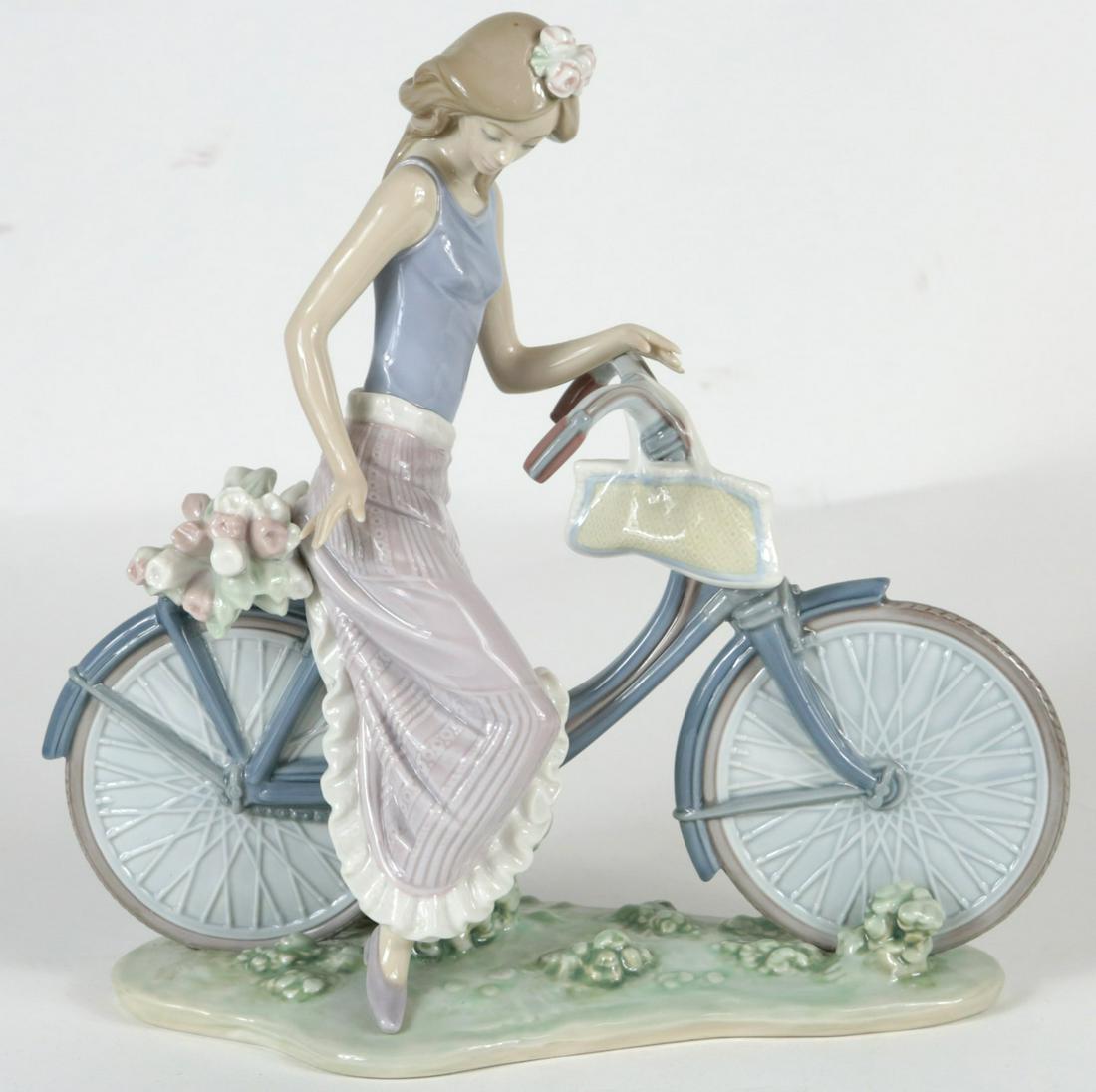 LLADRO 'BIKING IN THE COUNTRY' PORCELAIN FIGURINE: Lladro porcelain figure depicting a girl on bicycle with flowers #5272. Marked to underside. Measures 10 1/4" height x 10 1/4" length.