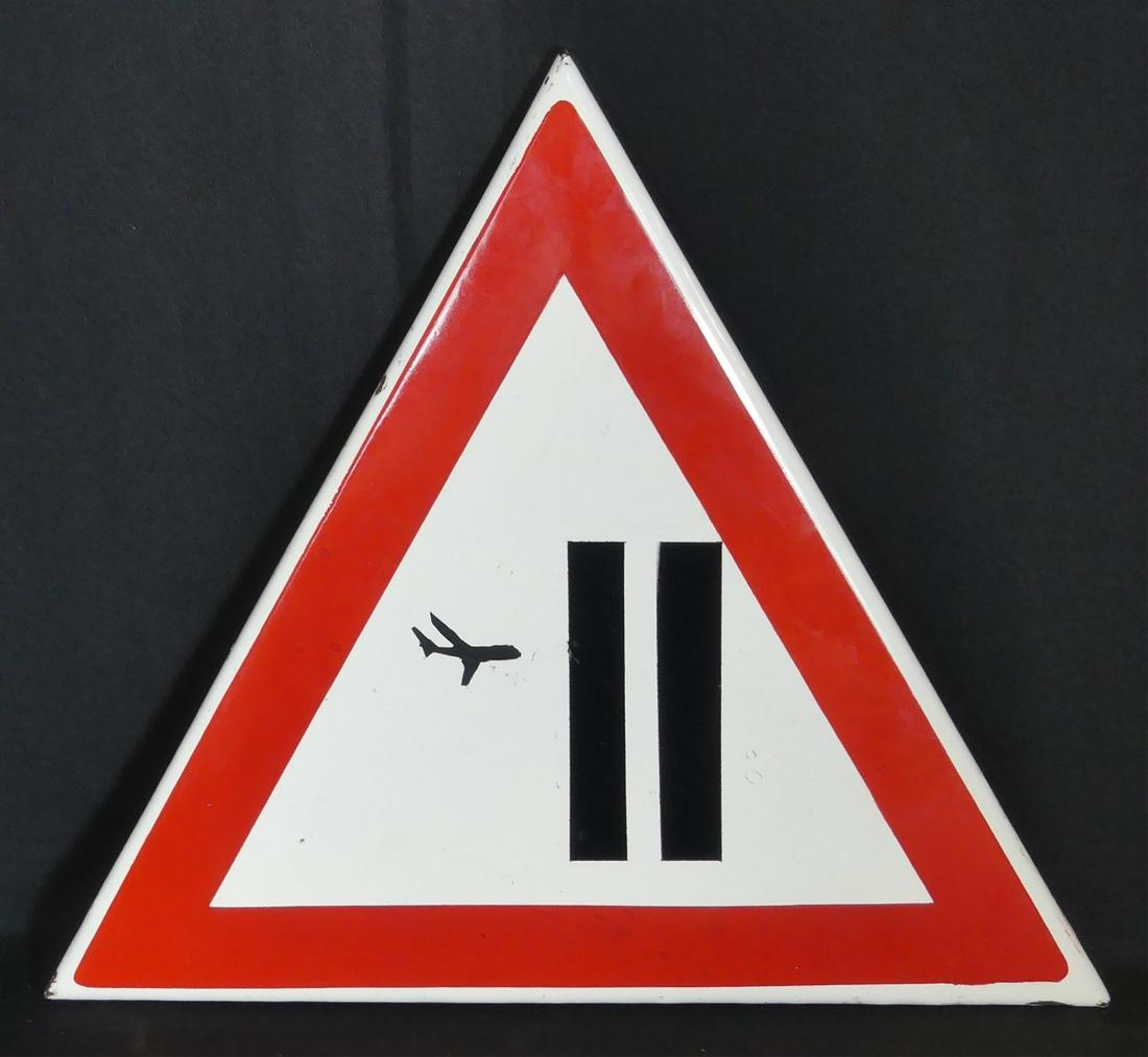 BANKSY TWIN TOWERS WARNING SIGN: Enameled metal warning sign of triangular form. Depicts an airplane and the Twin Towers of New York in the manner of Bansky. Measures 15" width x 13" height.