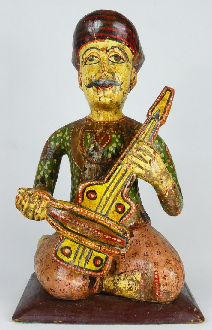 PERSIAN POLYCHROMED WOOD MUSICIAN FIGURE: Persian carved and polychromed wooden figure of a seated man with guitar. Measures 16 1/4" height.