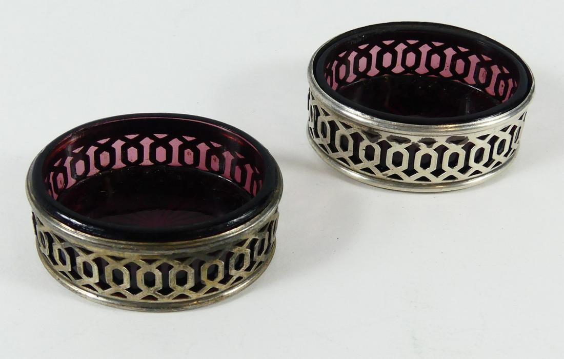 PR STERLING SILVER & AMETHYST GLASS SALT CELLARS: Pair of sterling silver salt cellars having amethyst glass liners. Each measures 1 7/8" length and is marked sterling to underside. Total silver weight 0.5ozt.