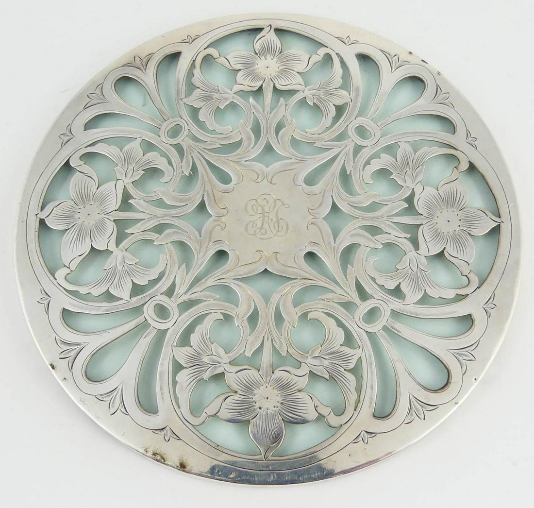 TIFFANY ART NOUVEAU STERLING SILVER TRIVET: Antique Tiffany & Co sterling silver over glass trivet. Round with floral overlay. Hallmarked and marked Sterling, 3092, 7in. Measures 7" diameter.