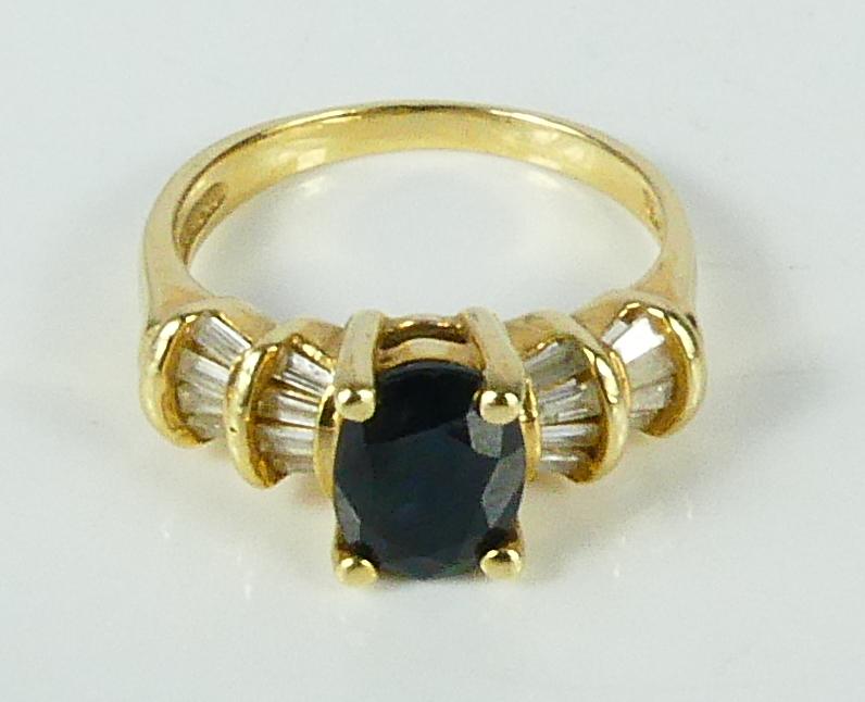 14kt YELLOW GOLD SAPPHIRE & DIAMOND RING: 14kt yellow gold ring prong set with one blue oval faceted sapphire. Baguette cut diamond accents. Stamped 14k inside shank. Ring size 7. Total weight 4.4g.
