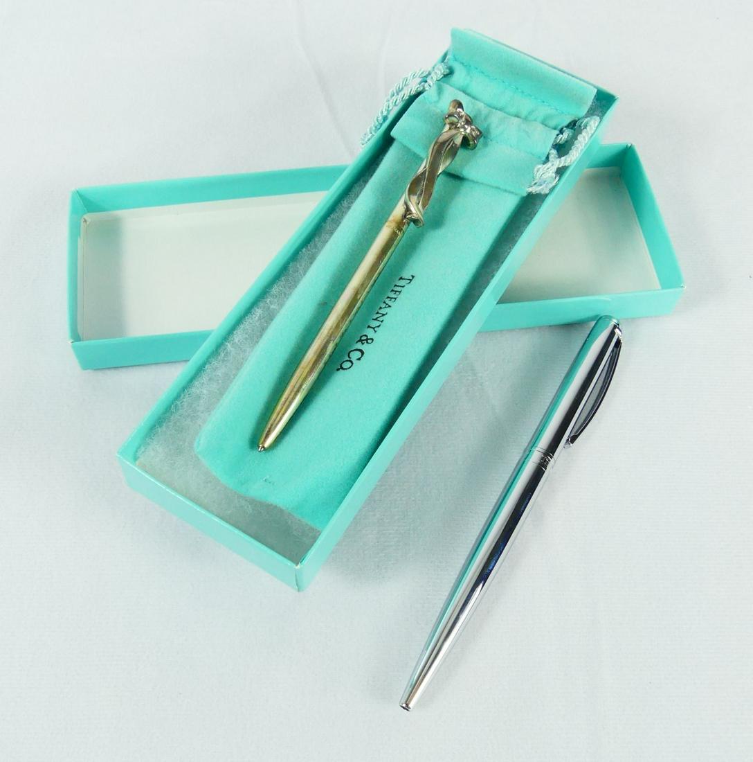 2pc TIFFANY & CO BALLPOINT PENS w BOX: Two Tiffany & Co ballpoint pens. Smaller with bow measures 4 5/8. Marked Tiffany & Co, Sterling, Germany. Larger measures 5 1/4" and is marked Tiffany & Co, Germany. Includes box and bag.