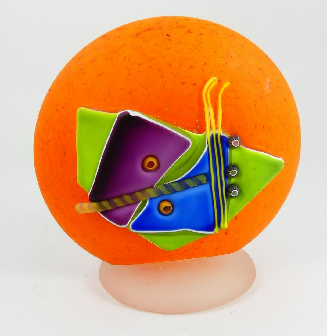 JAMES R WILBERT ABSTRACT ART GLASS SCULPTURE: James R. Wilbert studio art glass sculpture. Abstract decoration over a mottled orange disc. Signed to verso. Measures 6 5/8" height.
