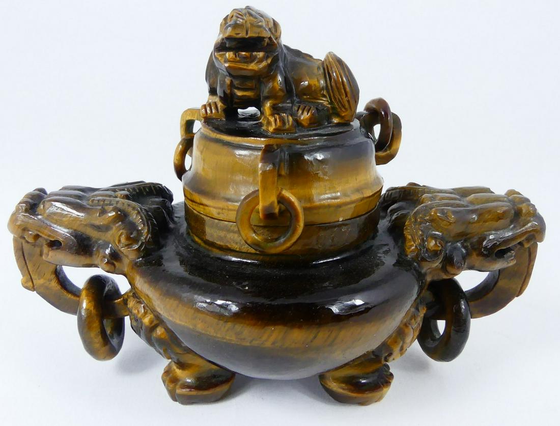 CHINESE CARVED TIGER EYE AGATE CENSER: Chinese carved tiger's eye agate center raised on tripod feet, with dragon ring handles and foo lion finial. Measures 4 3/4" length x 3 1/4" height.