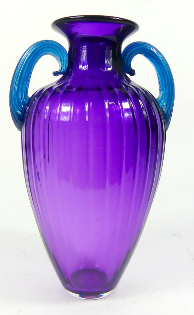 MELANIE GUERNSEY STUDIO ART GLASS VASE: Melanie Guernsey studio art glass vase having an amethyst body and blue scrolled handles. Signed to side of base and dated 1992. Measures 10 1/4" x 6" x 5".
