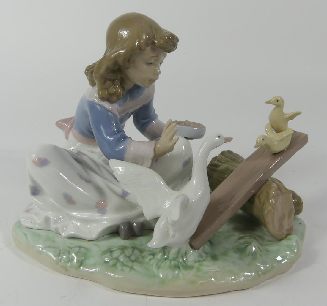 LLADRO 'BARNYWARD SEE SAW' PORCELAIN FIGURINE: Lladro porcelain figure depicting a seated girl feeding geese. Titled 'Barnyard See Saw' #6025. Marked to underside. Measures 8" length.