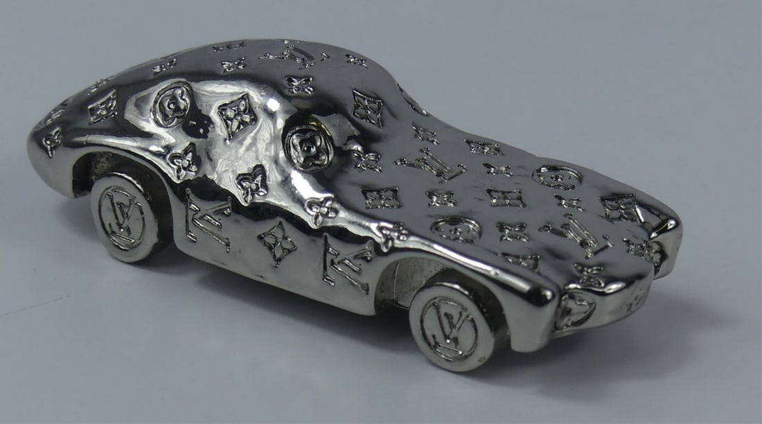 LOUIS VUITTON DIE CAST CAR: Louis Vuitton die-cast car. Monogrammed throughout. Marked Louis Vuitton Paris to underside. Likely an Aston Martin or Porsche. Approx 1/64 scale. Measures 2 1/4" l x 1" w.