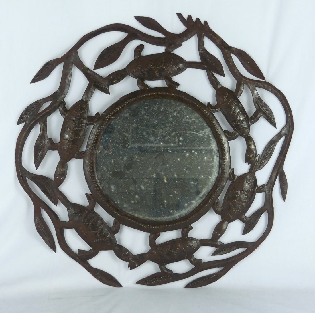 JULIO BALAN HAITIAN METAL SCULPTURAL MIRROR: Julio Balan (Haitian) metal sculpture depicting turtles and leaves with round mirror to center. Measures 23" x 23".