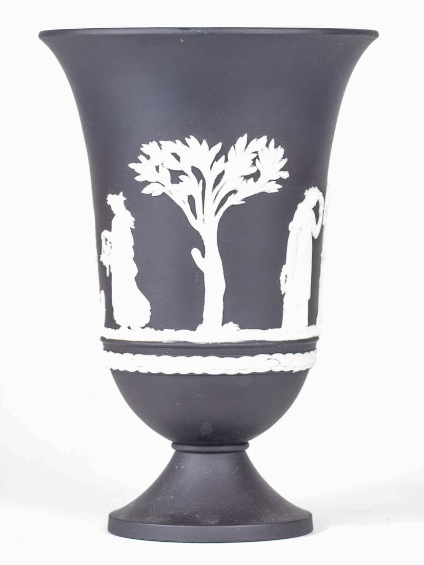 WEDGWOOD BLACK JASPERWARE FOOTED VASE: Wedgwood jasperware footed vase having a black finish vessel decorated in white classical reliefs. Marked to underside. Measures 7 1/4" x 5" x 5".