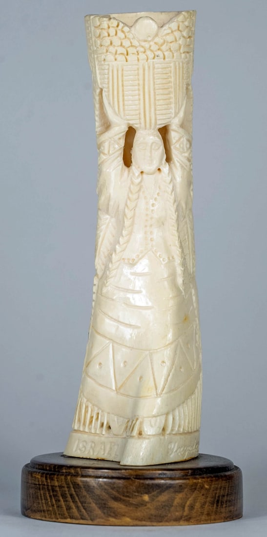 ISRAELI CARVED OX BONE SCULPTURE: Israeli carved ox bone sculpture depicting a woman with basket. Signed Yagudaer (?) and inscribed Israel. Measures 9 3/4" x 4 1/4" x 4 1/4".