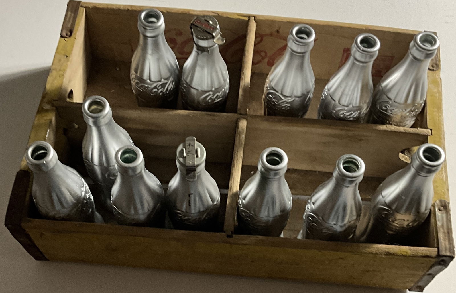 ANDY WARHOL 'YOU'RE IN' COCA COLA BOTTLES w CRATE: Andy Warhol (1928-1987) 'You're In' Spray Painted Coca Cola Bottles (Grouping of 12). One Cap initialed on top A.W. in black ink. Measures 12 x 18 inches crate.