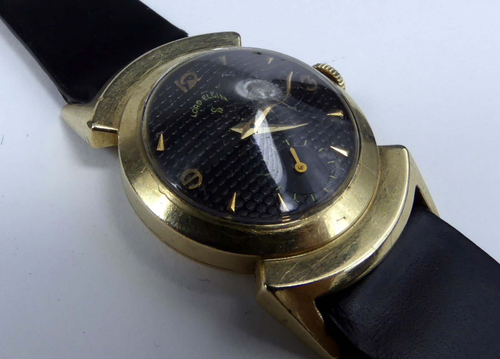 LORD ELGIN BLACK KNIGHT WRISTWATCH: Rare Lord Elgin Black Knight wrist watch. Black biscuit dial, fancy lugs and original pyramid crystal dial. 21j; cal 680; gold filled. Case measures approx 27mm; lug to lug 40mm; overall 9".