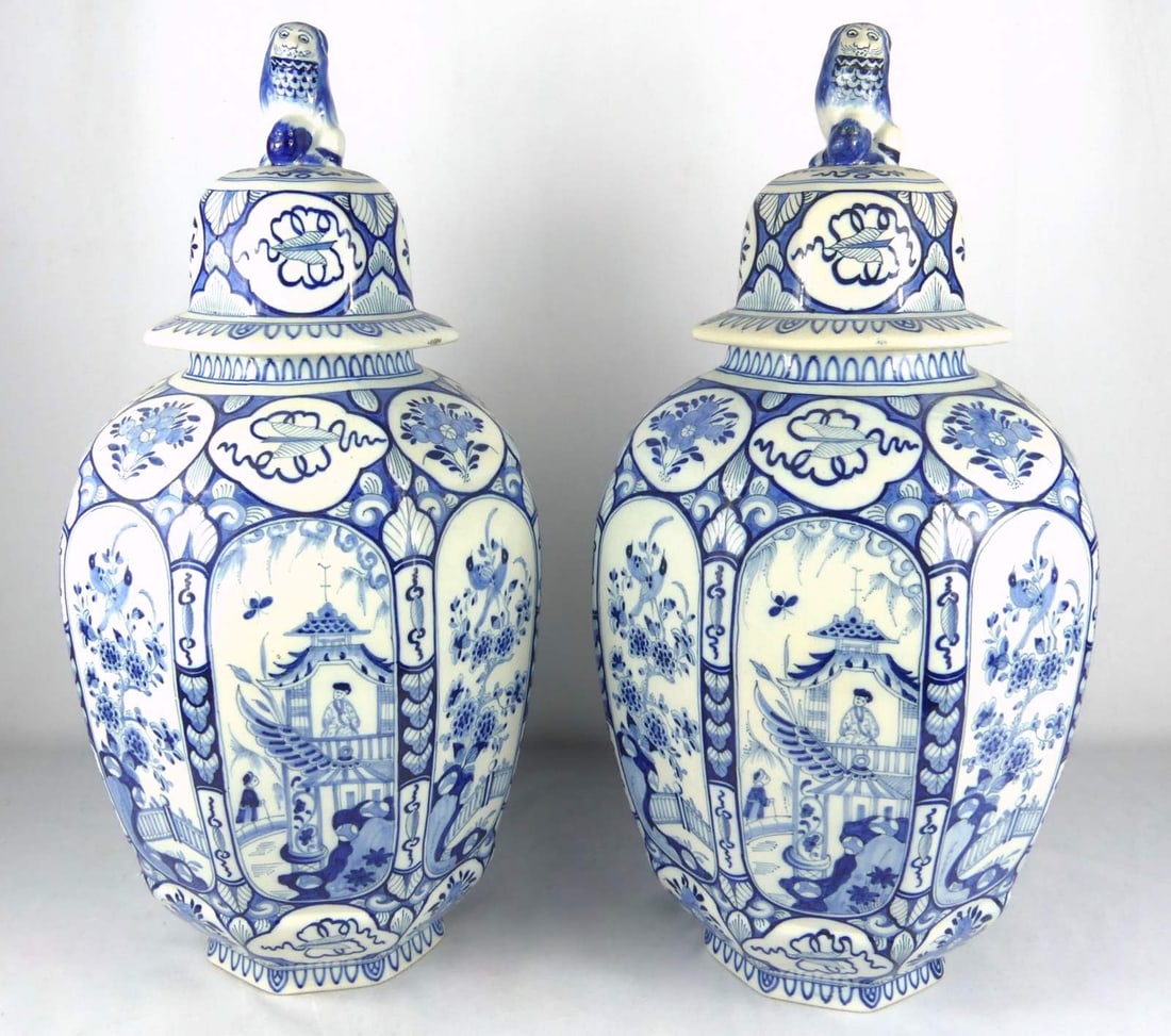 PR DELFT BLUE & WHITE PORCELAIN COVERED JARS: Pair of Delft Chinoiserie blue and white porcelain ginger jars with foo lion finials. Each marked to underside. Each measures 19 1/2" x 10 1/2" x 10 1/2".
