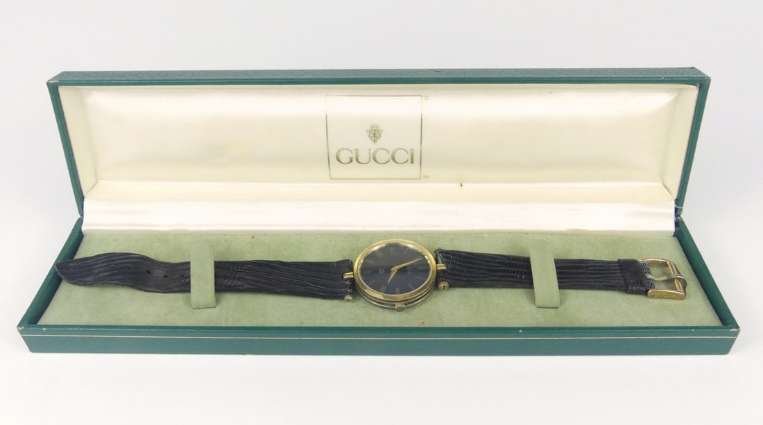 GUCCI VINTAGE SHERRY LINE QUARTZ WRISTWATCH w BOX: Gucci Vintage Sherry Line quartz wrist watch. Black dial and black enamel back. Includes original box. Note: missing one strap screw. Case measures 30mm diameter. Box measures 9 1/2" x 2 1/2" x 1 1/4"