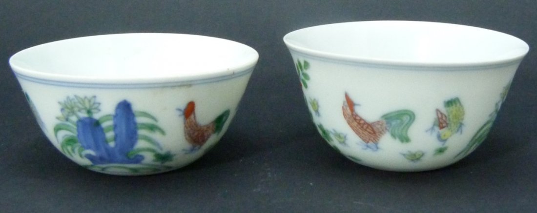 TWO QING DYNASTY DOUCAI PORCELAIN WINE CUPS: Two Qing Dynasty Doucai wine cups. Porcelain. Decorated with chickens and cactus. Bottom holds 6 character Ming Chenghua mark. Both measure approx 1 1/2" (3.81cm) height by approx 2 1/2" (6.35cm) diam