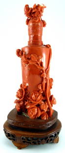 LARGE CHINESE CARVED RED CORAL SNUFF BOTTLE: Large antique carved Chinese red coral snuff bottle with floral decoration carved in high relief and draped with a ribbon around the neck of the bottle. Includes a carved fitted wood base. Measures ap
