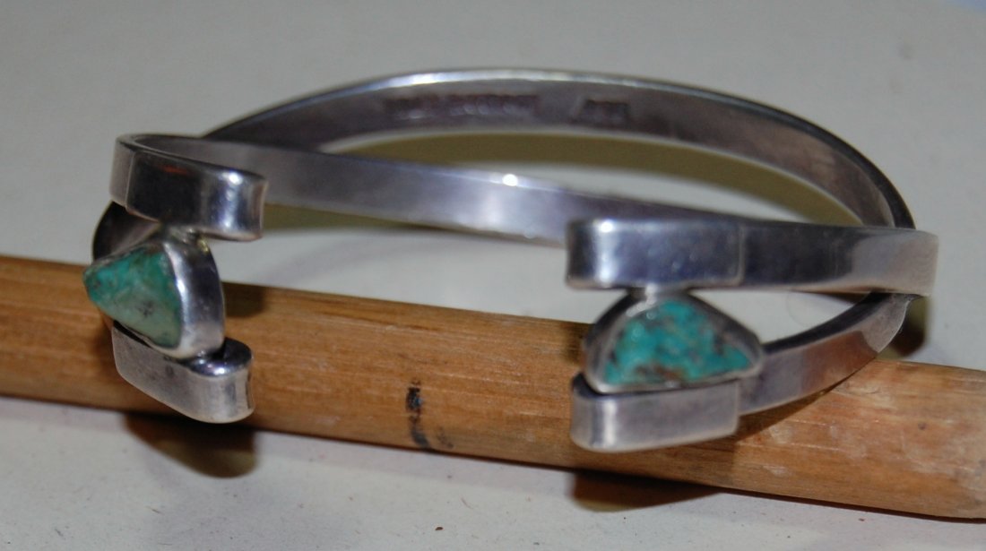 Turquoise Bangle Lilly Barrack: Signed and marked .925, adorned with two baroque pear-shaped turquoise stones. 2.4 diameter. 6.1 cm. 27 grams. Southwest jeweler in Navajo style. No Buyer's Premium, reserve is starting price.