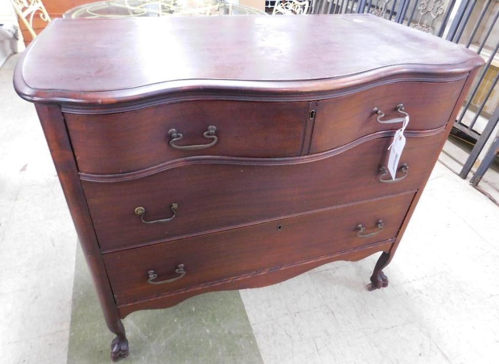 serpentine front mahogany chest: ornate brass drawer pulls with claw feet on casters. 36 1/2 inches tall by 42 1/2 inches wide by 22 inches deep