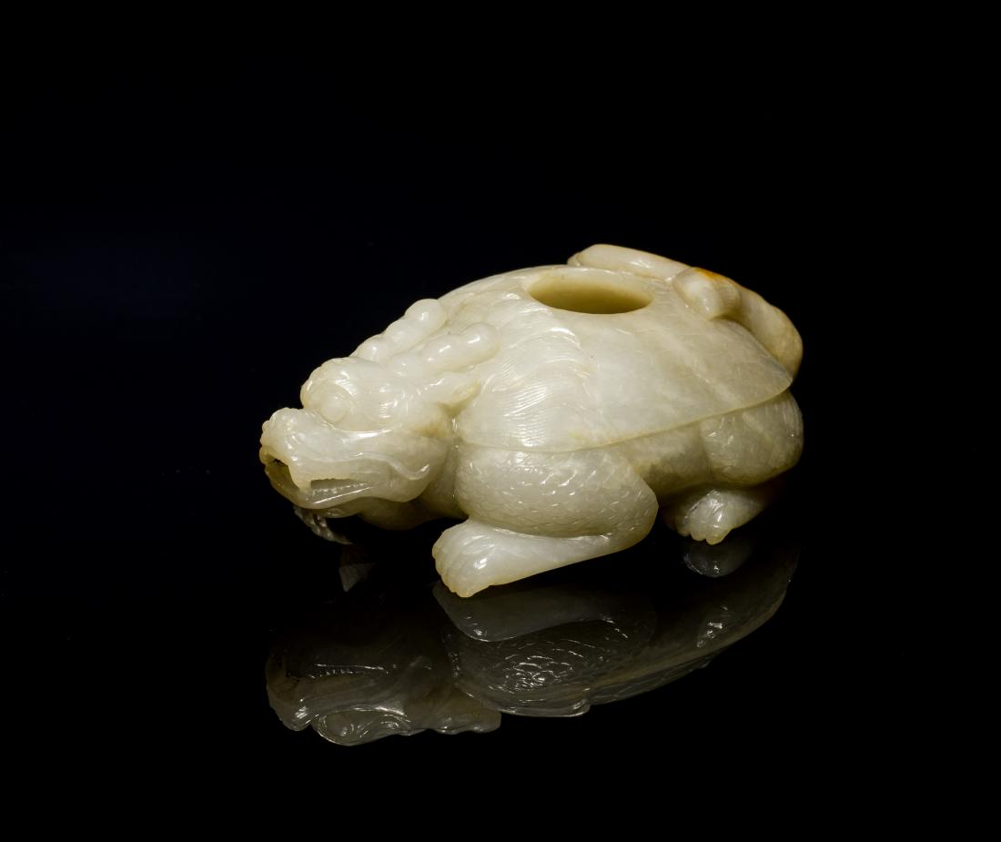 18th Antique White Jade Washer: Carved with fang teeth and bulging eyes, its head slightly swayed to its left and legs tucked underneath, the back covered with tortoiseshell incised with key-fret, well hollowed with a hole in the ce
