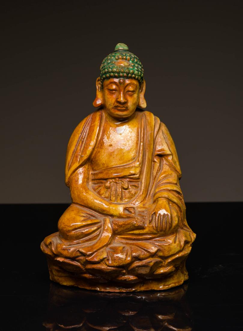 Ming Antique Yellow Glazed Buddha: The figure seated in dhyanasana on a lotus plinth with the right hand in dhyanamudra and the left lowered in bhumisparsa mudra, wearing a shawl over the shoulder and loose robes, the face with serene