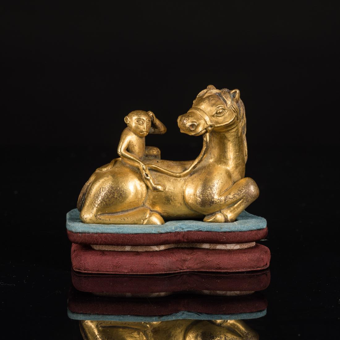 19th Antique Gilt Bronze Horse and Monkey: The horse cast recumbent with four legs tucked underneath its body, with its head turned backward, its pronounced mane and bushy tail finely incised, further depicted a monkey sitting on the horse bac