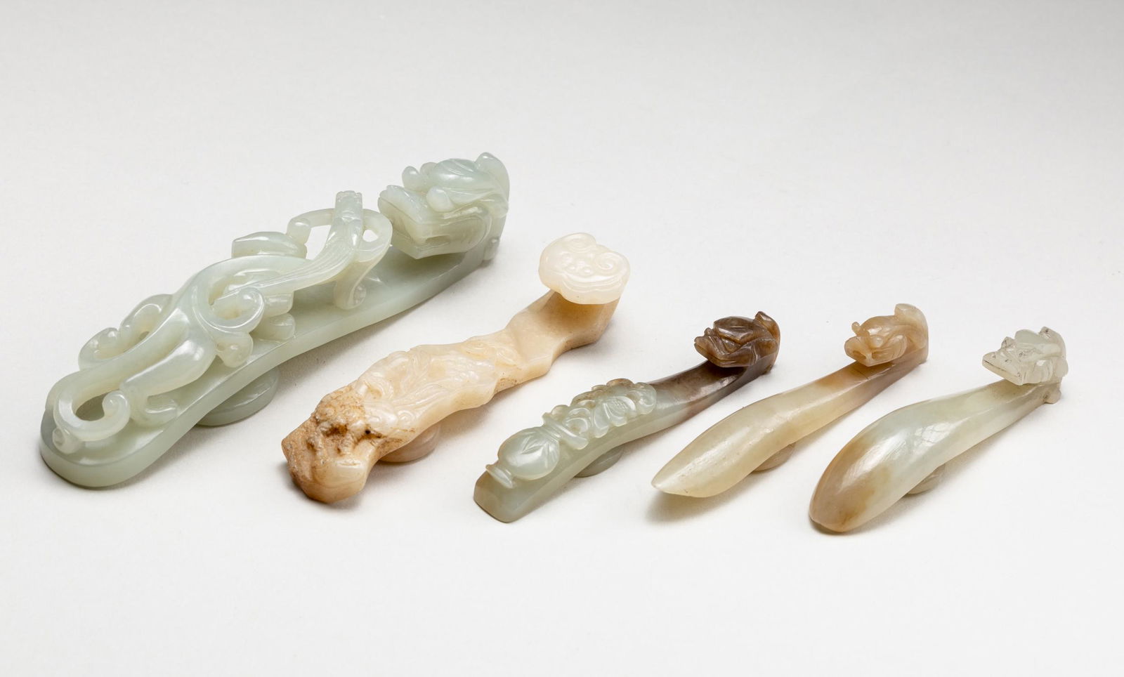 Set Of Chinese Antique Jade Belt Hooks: Comprising: three dragon belt hooks, and one ruyi hook, each with a horned dragon forming the hook, one large shaft finely carved with a chilong crawling towards the dragon headed hook, an oval button