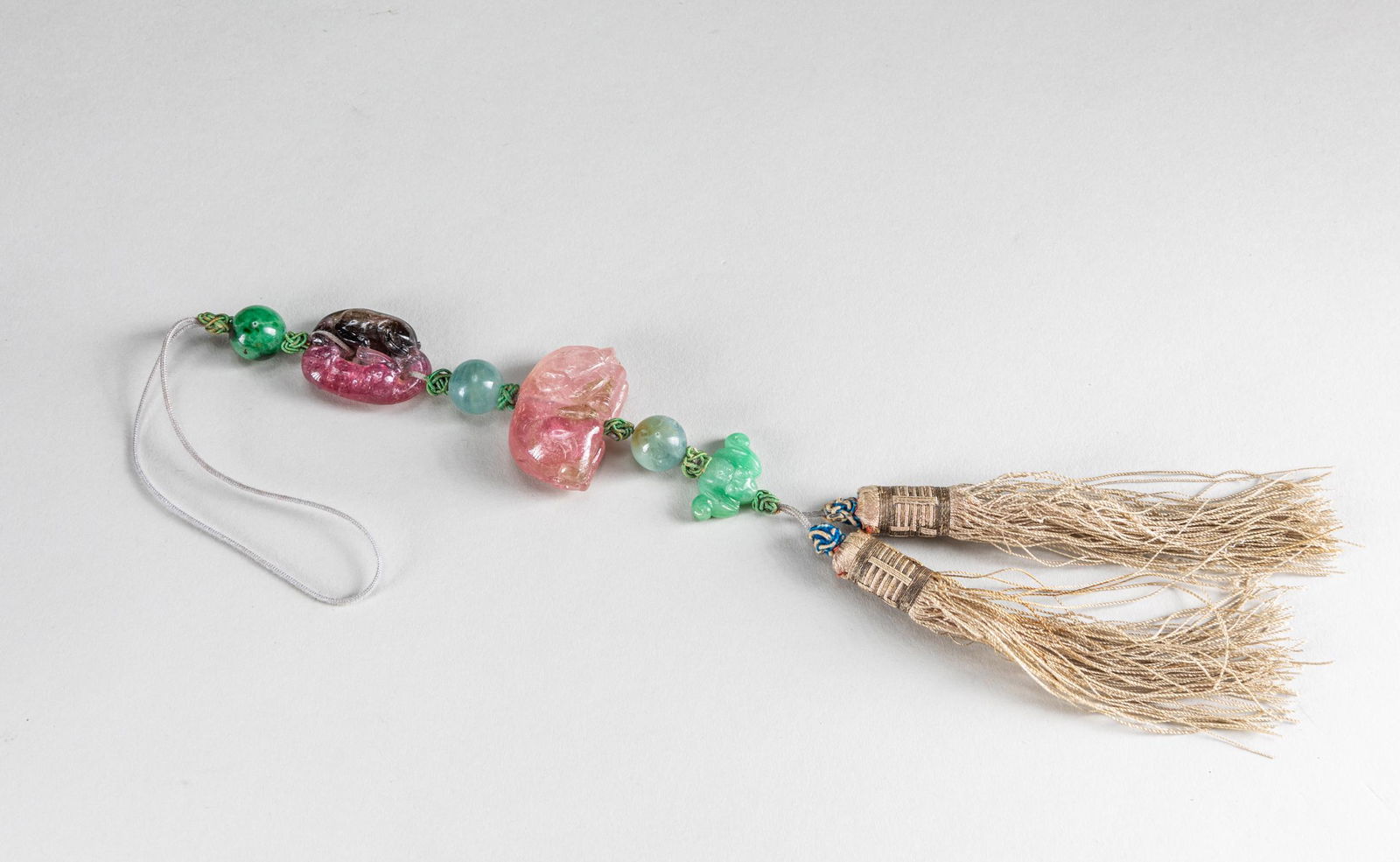 19th Important Chinese Antique Tourmaline Pendant: The pendant starts with one tourmaline pendant, skillfully worked in the form of a pair of mythical beasts arranged head to tail, each rendered with globular bulging eyes and a pronounced spinal colum