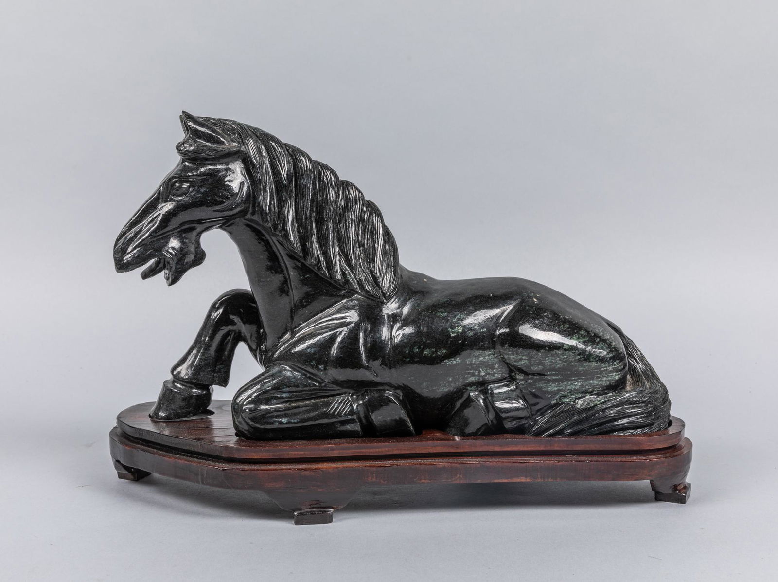 1890-1930 Chinese Antique Spinach Jade Horse: Carved in the form of a recumbent horse, lying on its side with both hind legs turned up, its finely incised curled along the length of the lower right leg. The estate of Elmry Thrumki ,1998 . 14.1*9.
