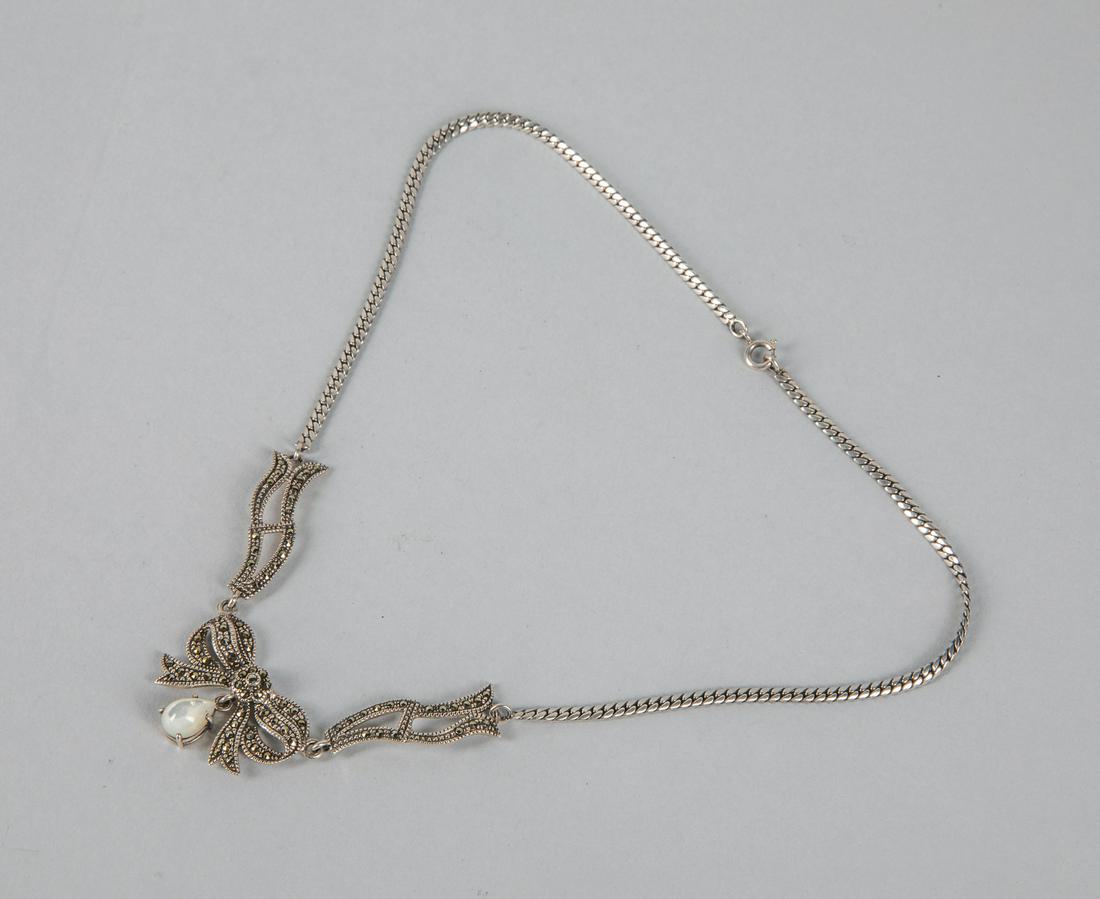 Designed Marcasite Bow Silver Necklace: Marked 925. Marcasite bow silver necklace. A mother of pearl drop beads suspended on the end. 8.25 inch L.