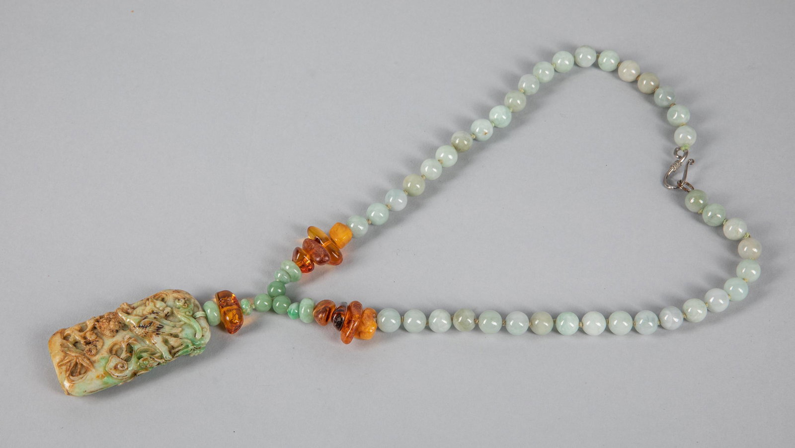 Chinese Export Jadeite & Amber Necklace: The necklace composed by jadeite & amber beads, a carved jadeite pendant on the end. Silver link. 14 inch L.