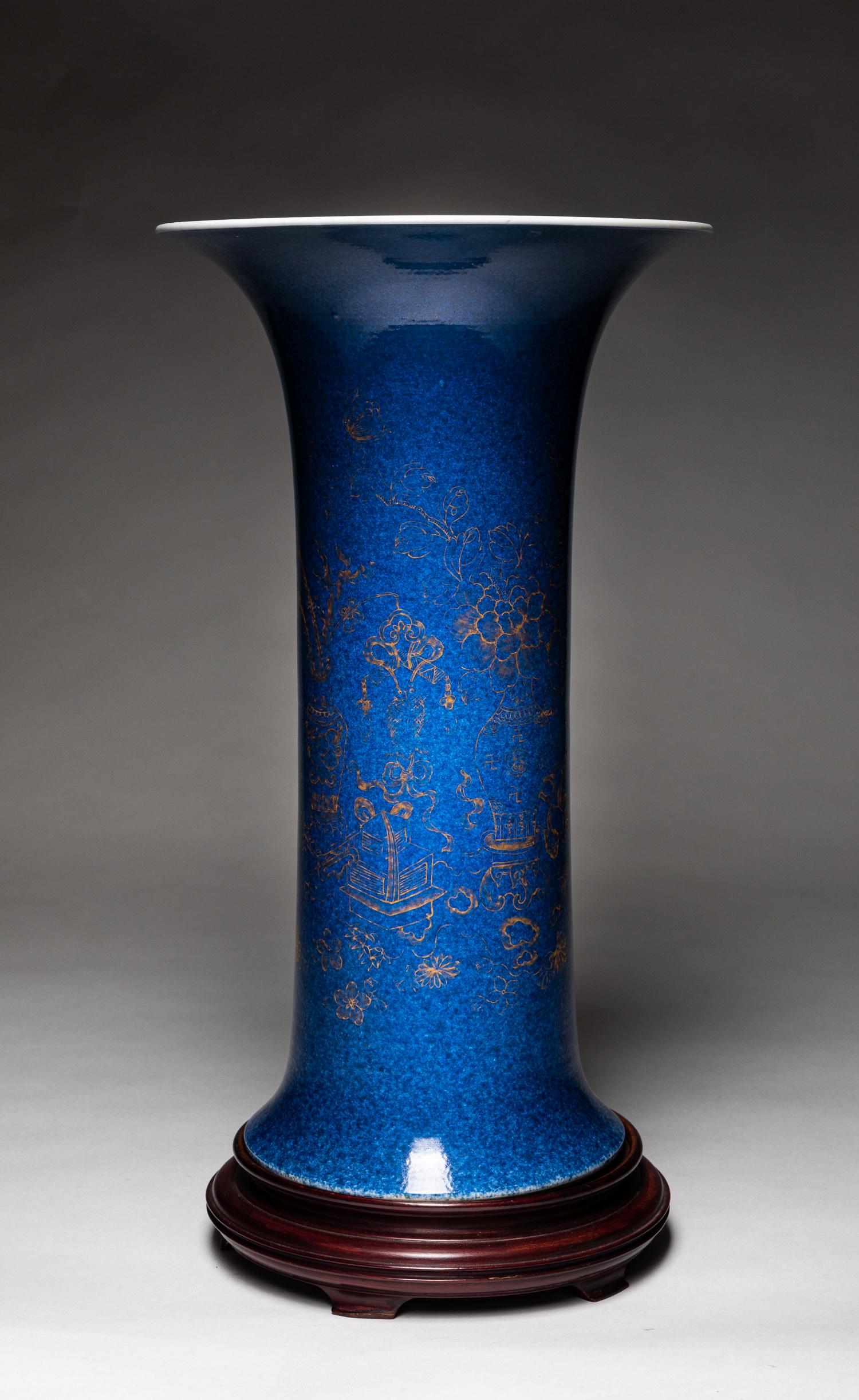 Tall Chinese Gold Blue Glazed Porcelain Beaker: The cylindrical body rising from a spreading foot to a tall flaring neck, painted around the exterior in gold tone featuring jardiniere growing exotic flowers, interspersed with lotus head, all agains