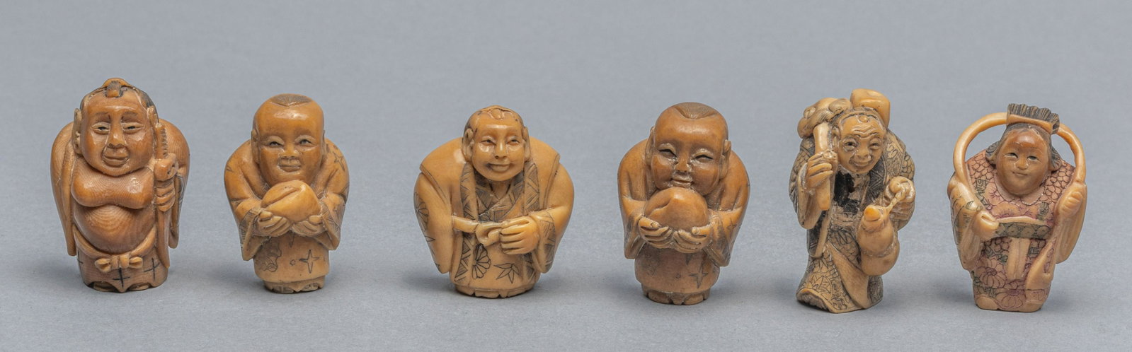 Group of Japanese Taisho Period Vegetable-Ivory: Group of six Taisho period vegetable-ivory netsuke carved figures. Decorated with figures holding peach, crutch, or gourd. 1.5x1 inch (each) 62g (total).