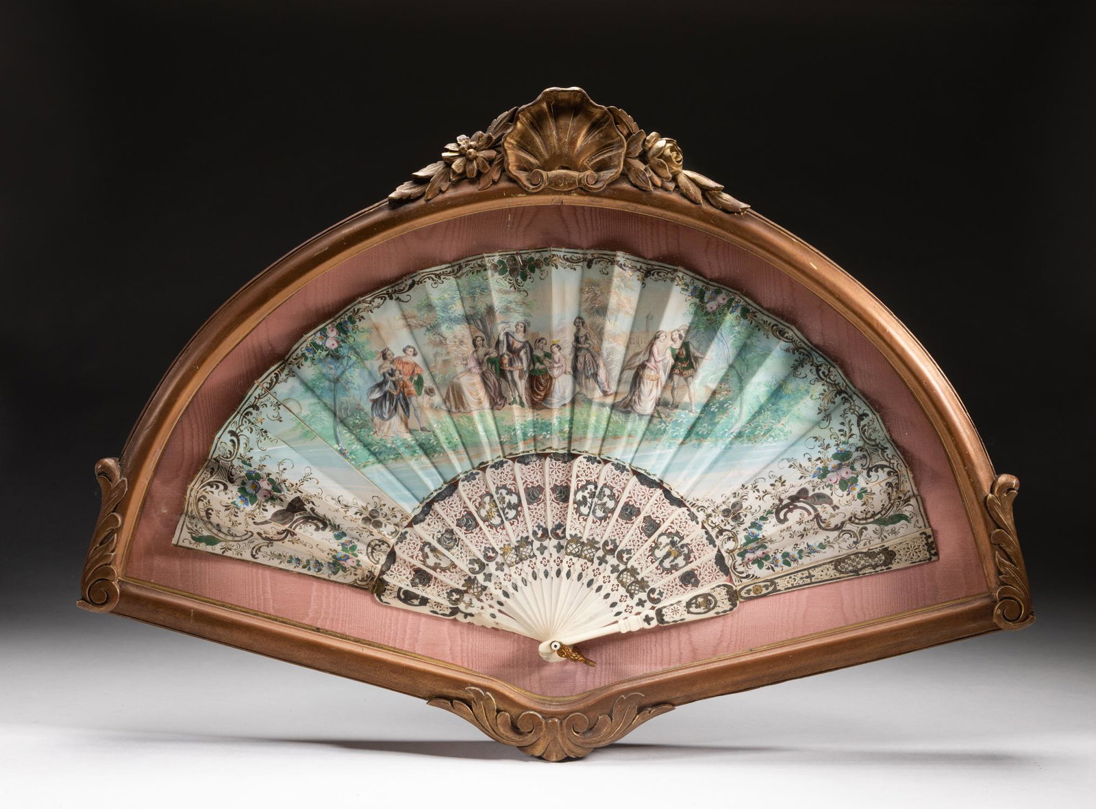 Antique Spain Hand Painted Bone Hanging Fan: A Spain hand painted bone fan, the guards and sticks pierced, carved, and gilted, the leaf painted with nine figures near a riverbank, sides painted with complicated and gilt floral pattern, with a fi
