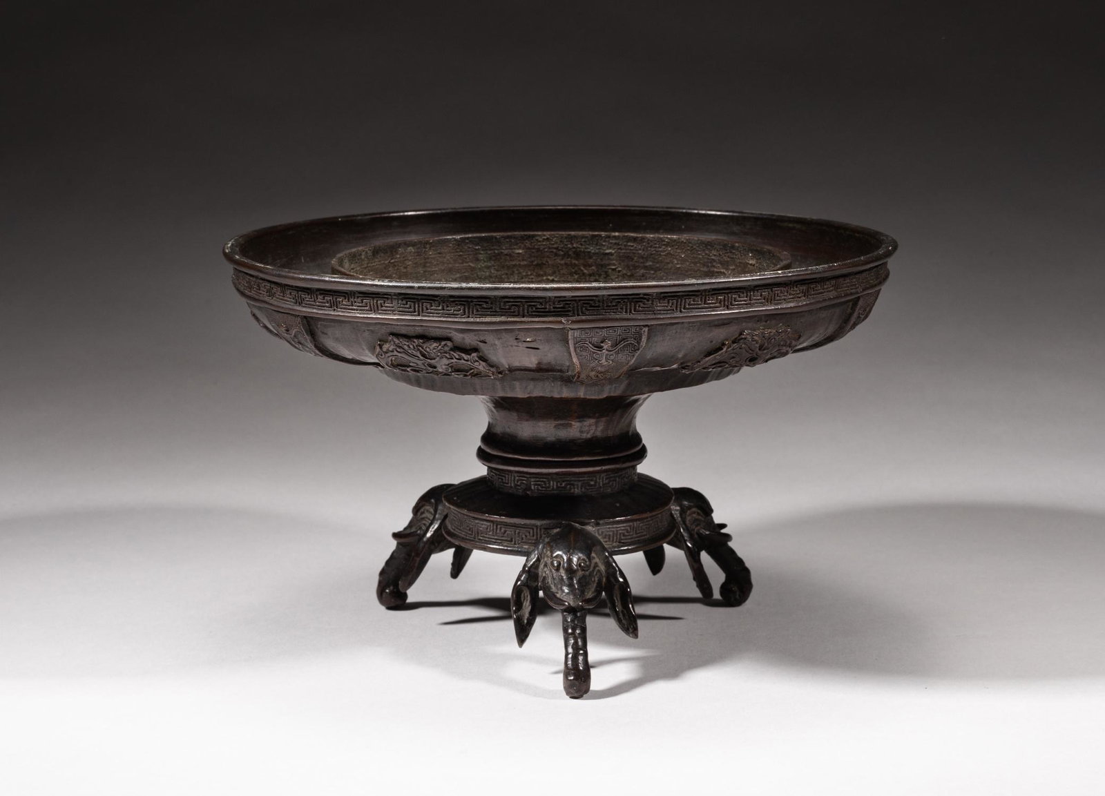 Japanese Meiji Bronze Vase: Japanese Meiji type bronze vase carved with archaistic patterns to the exterior and key fret motifs to the mouth rim, base with a mark, with a three-foot stand carved in elephant head type and with ke