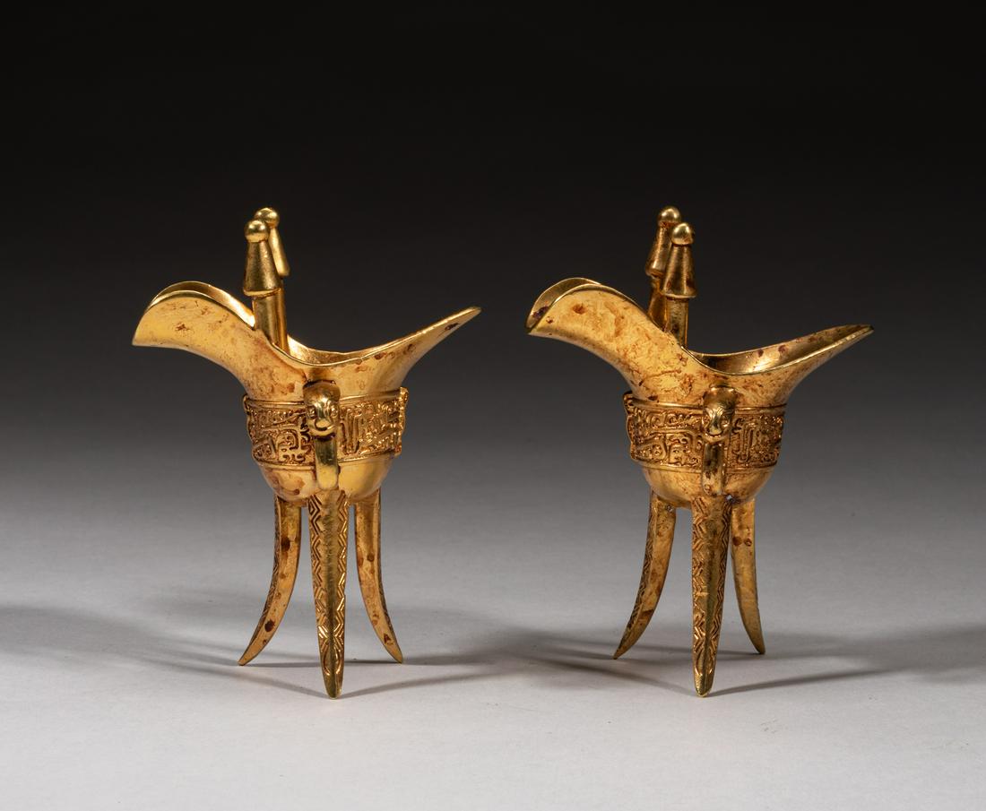 Pair Chinese Gilt Bronze Cups: A pair of antique Chinese gilt bronze wine cups in the former of ancient jue, each with an archaic beast type handle, carved with traditional patterns. 4.1*3.1*1.9inch. The Estate of the H. Lopez. Hol