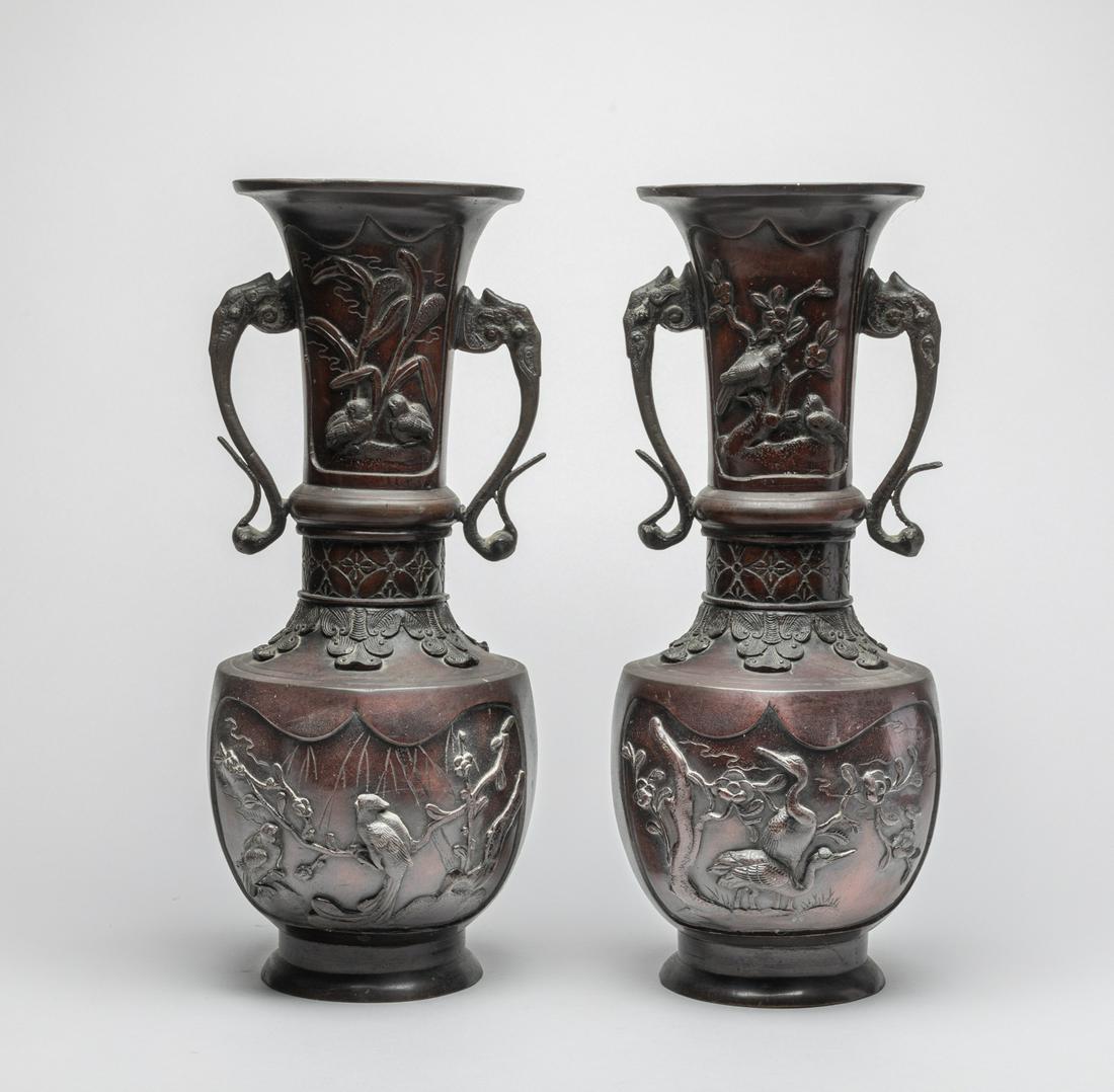Pair Tall Japanese Meiji Bronze Cabinet Vases: The ovoid body rising from a splayed foot to a tall neck and a flared rim, the body and neck carved with birds and flowers in high relief, the shoulder with floral and leafy motifs, with a pair of ele