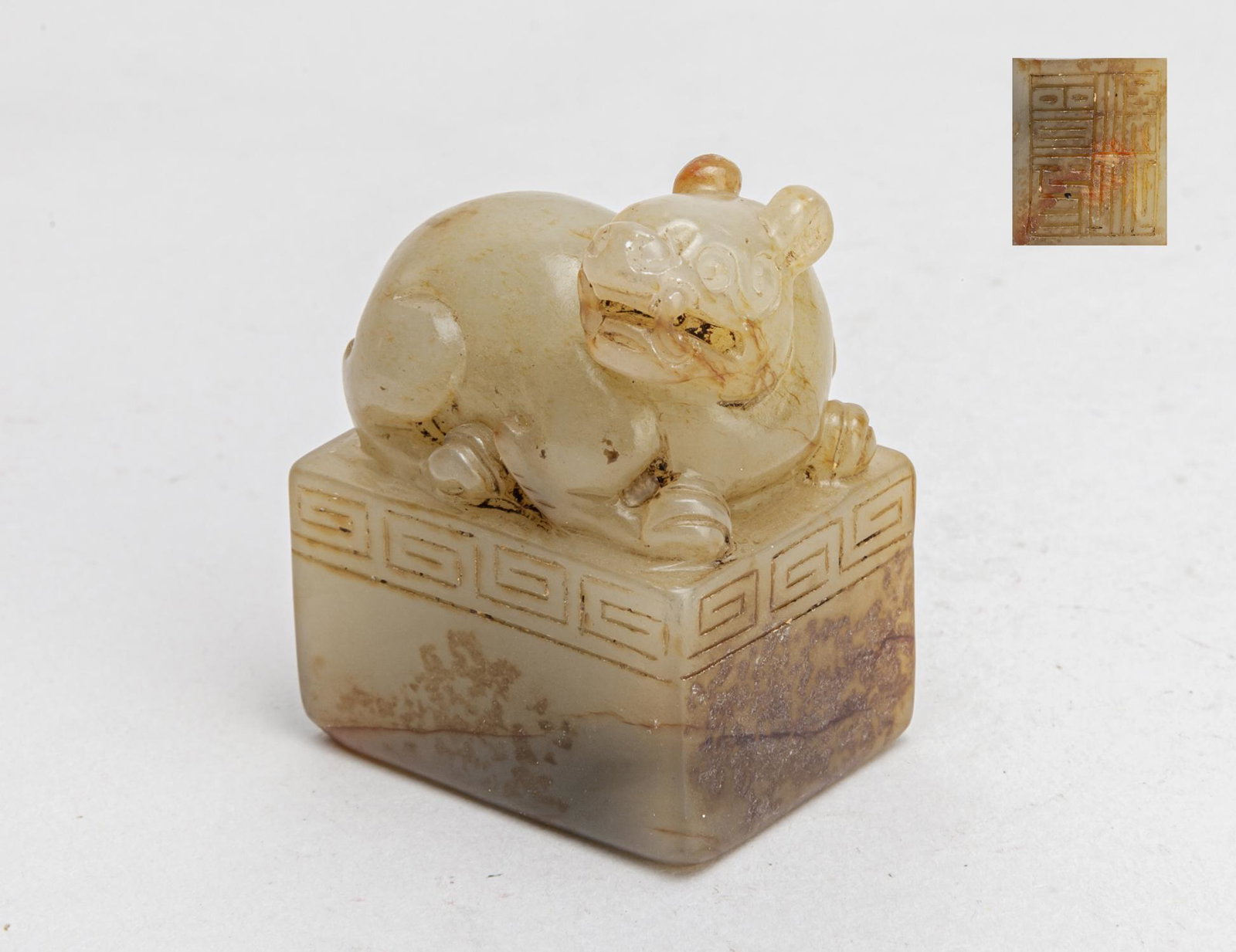 Chinese Russet Jade Seal: Of rectangular section, surmounted by a crouching beast with its head raised and turned right, the seal face incised with four characters, the stone of grayish-brown tone with russet inclusions. 2.05i
