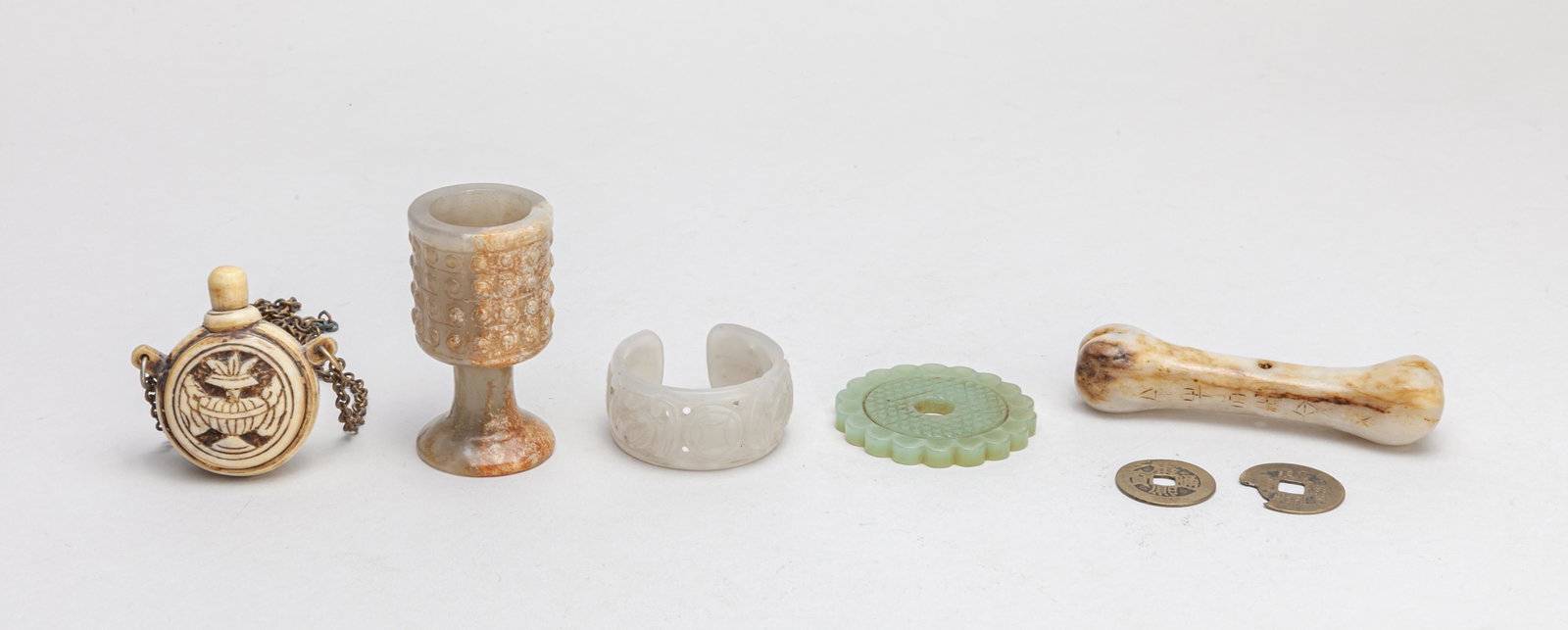 Estate Chinese Jade, Bone, Coins: 7 pieces in total, including Chinese coins, a bone type jade carving, a jade cup, a jade bangle carved and pierced with bats and coins, a jade bi and a bone snuff bottle of rounded form, carved with t