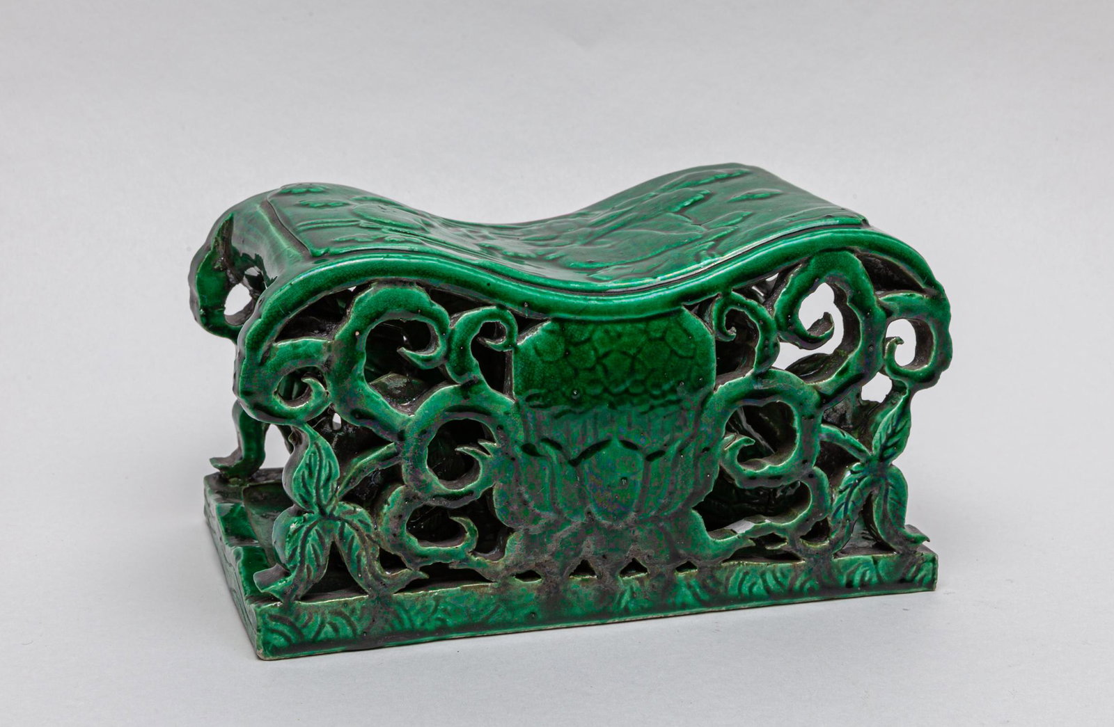 Chinese Turquoise Glazed Porcelain Pillow: The interior molded with a pair of ducks, below the top side carved with lotus and clouds, the flanks carved and pierced with flower scrolls, overall except the base applied with a rich turquoise gree