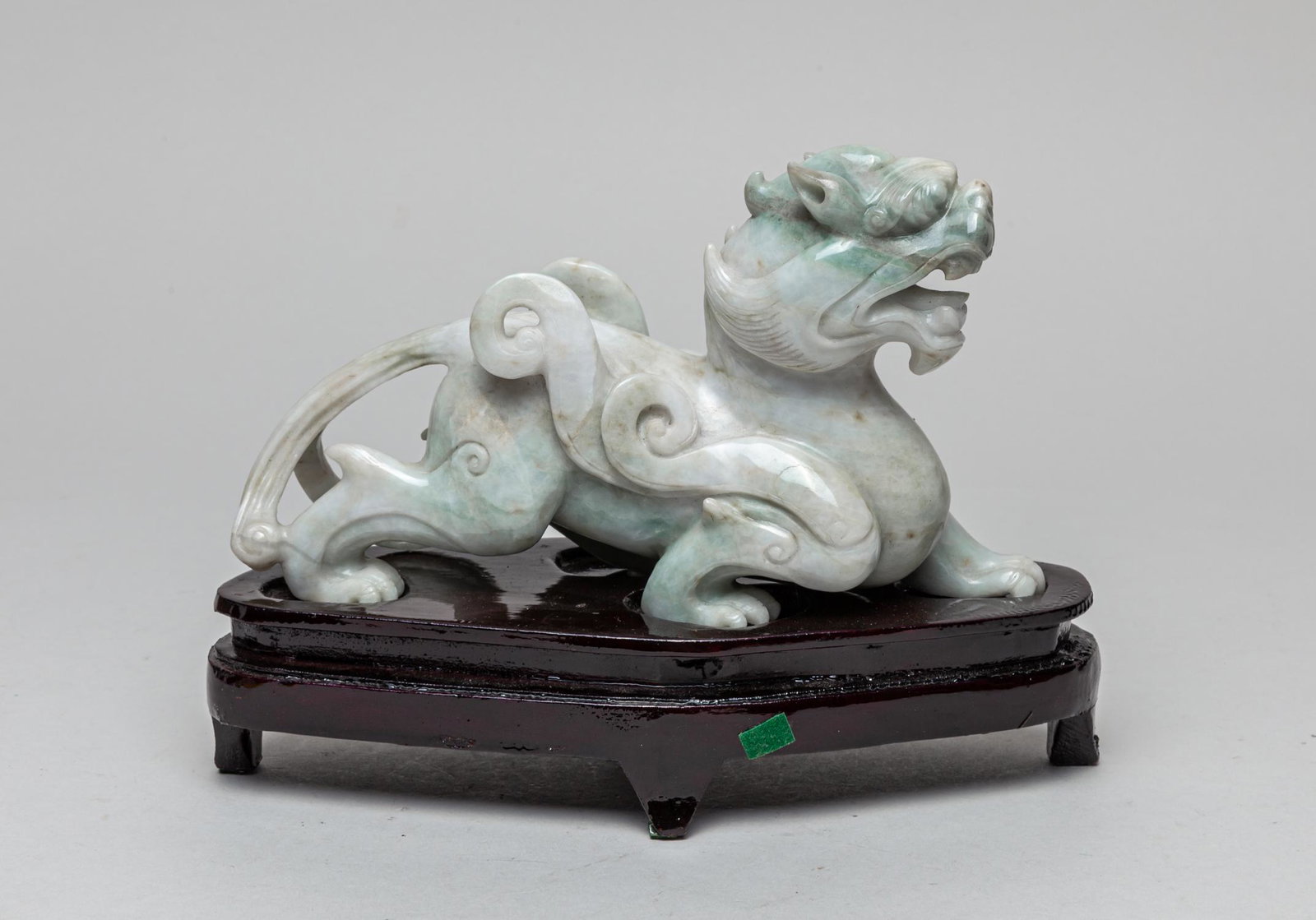 Large Chinese Jade Carved Table Sculpture: Rendered in the form of a beast crouching with the left front leg extending forward, portrayed with a pair of funnel-form ears and a horn swayed backwards, staring intensely through bulging eyes, the 