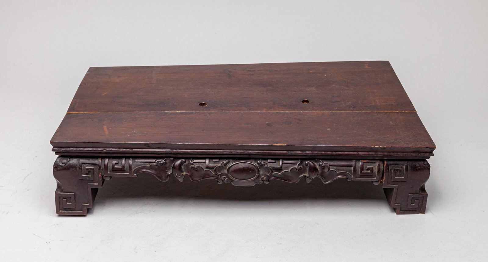 Large Chinese Carved Wood Stand: Of rectangular section, the top pierced with two holes, the sides carved with traditional fret motifs and bats. 20.6inch L, 11.5inch W, 4.5inch H.