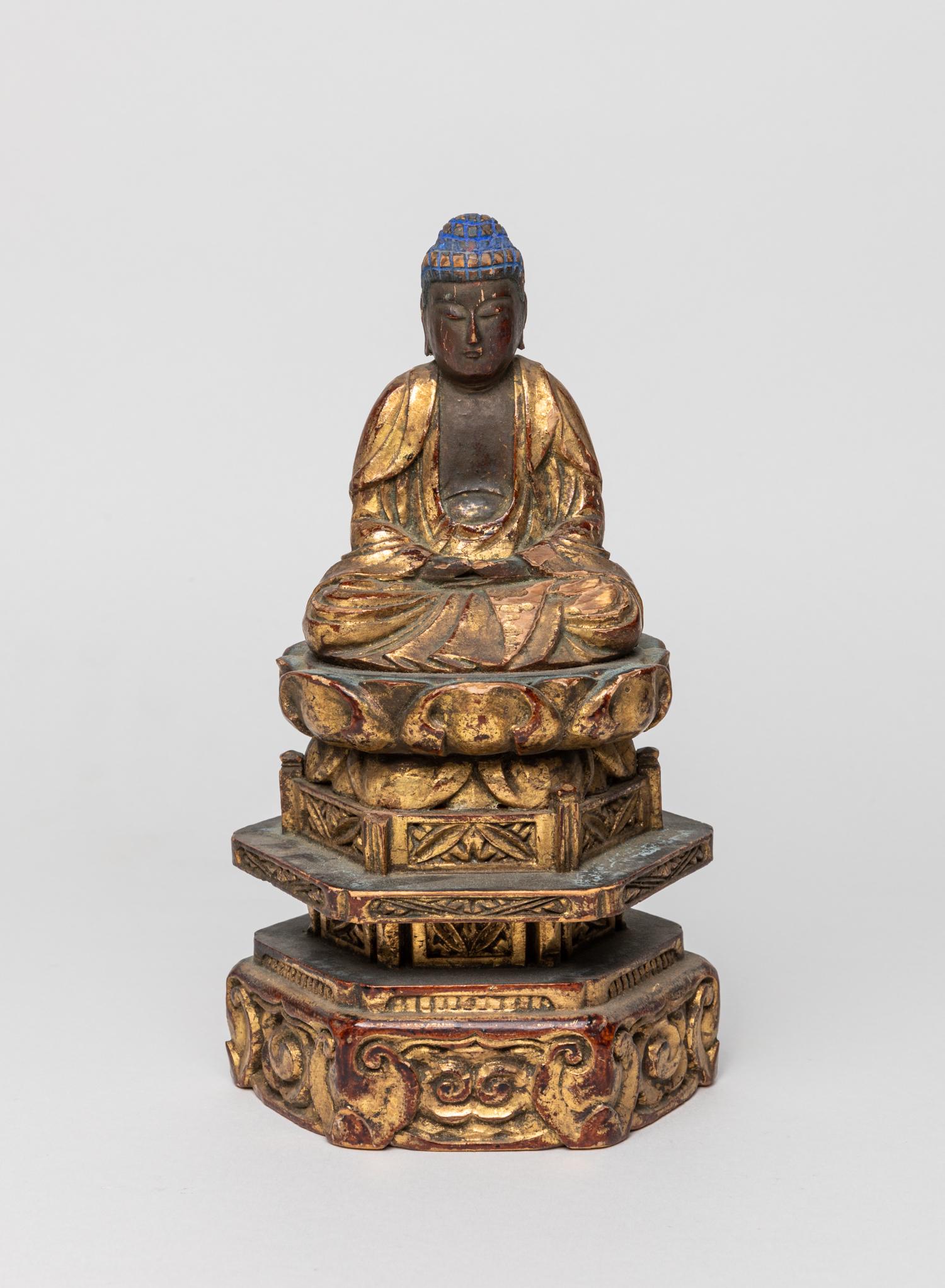 Antique Japanese Gilt Wood Buddha: Carved seated in dhyanasana on a lotus throne supported with a tall hexagonal stand, the arms lowered in dhyanamudra, wearing long robes opening at the chest, the face with a serene expression. 8inch 