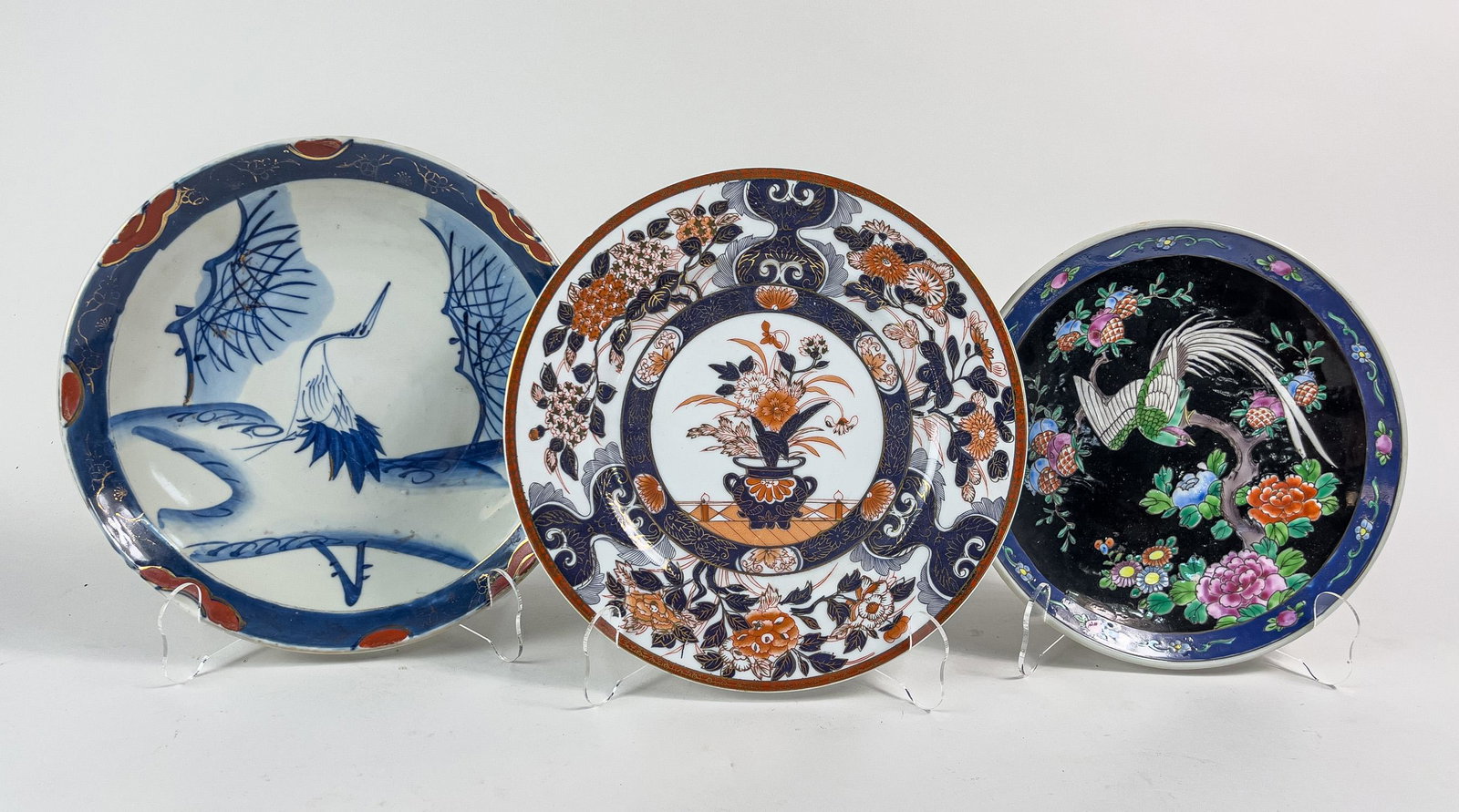 Set Vintage Japanese Porcelain Charger Plates: Set of three porcelain charger plates, the interior decorated with scenes of a crane among landscape, a bird moans blooming flowers, or various flowers in basket. 10.75inch D (largest).