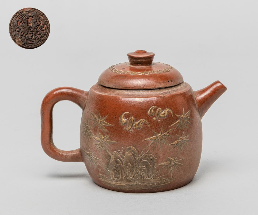 Chinese Yixing Zisha Tea Pot: The exterior decorated with bats, bamboo and rockery to both sides, the cover with continuous scrolling patterns, the base incised with a circular-shaped mark. 4inch L, 2.6inch W, 2.8inch H.