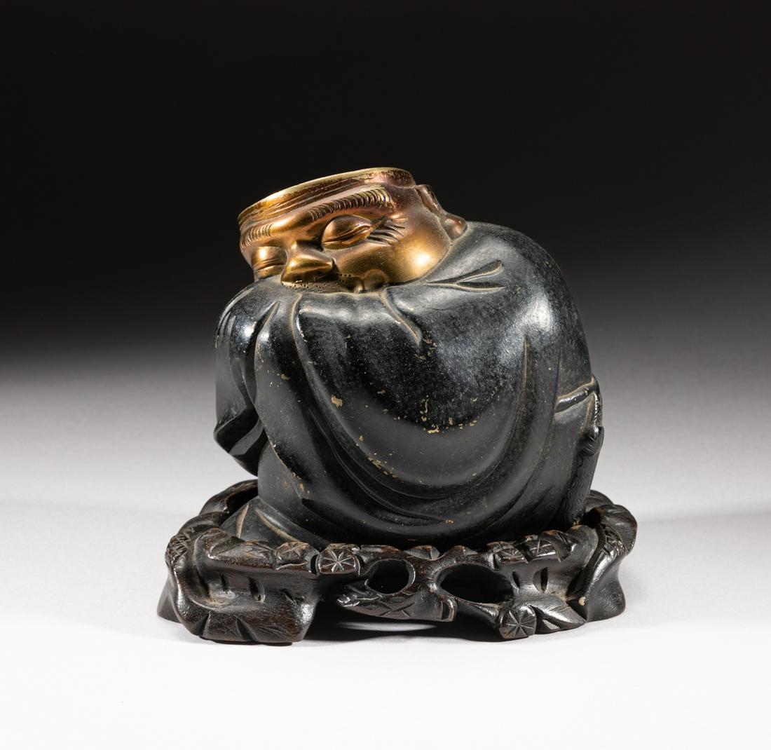 Japanese Taisho Metal Sculpture: Japanese style hollow metal sculpture, moulded as an old man dressed in a loose robe, the meditative face with closing eyes, prominent nose and a flat top, with a fitted wood stand. 4.5inch L, 3.9inch