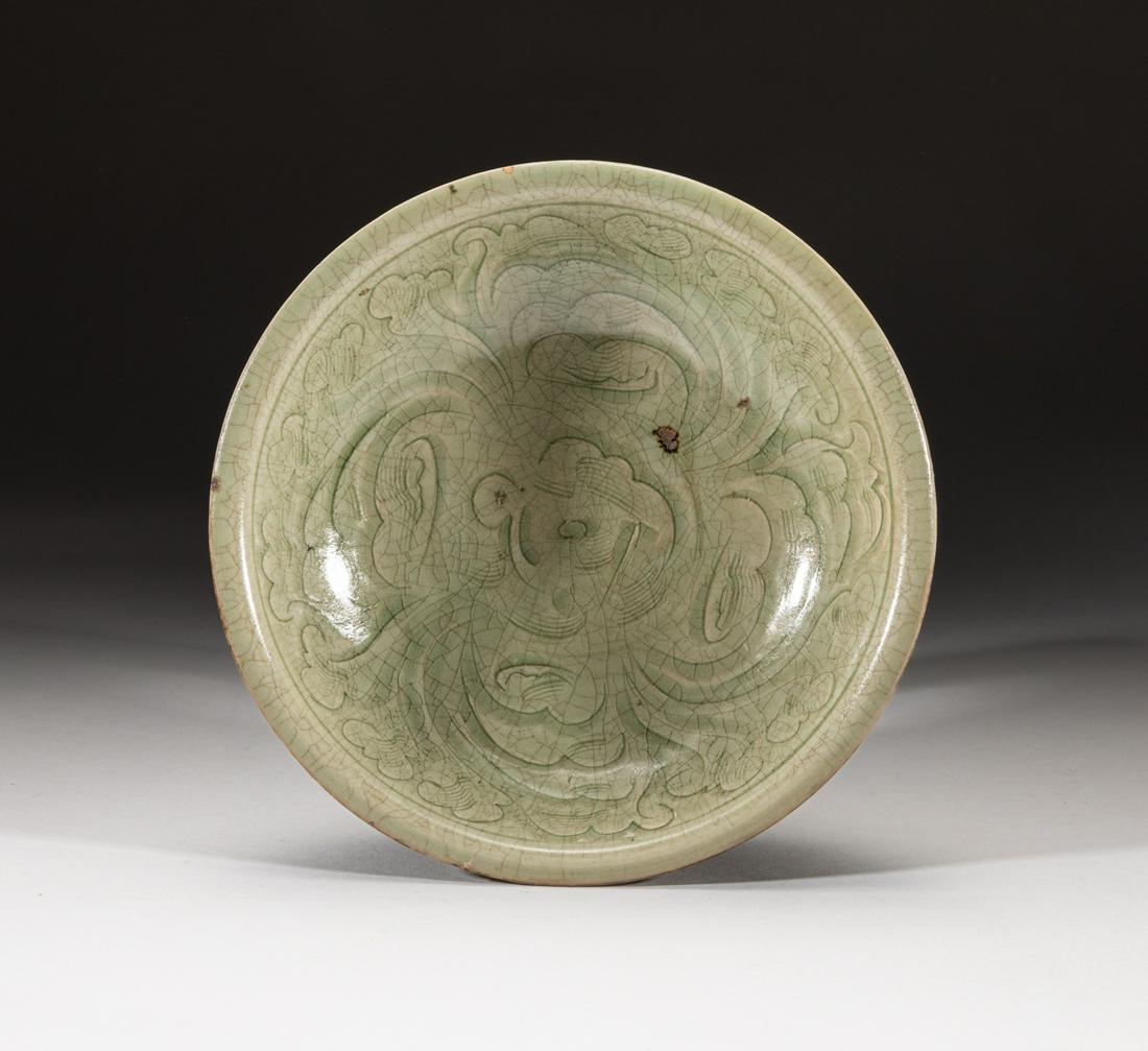 Large Chinese Yue Stoneware Porcelain Bowl: Molded with gently rounded sides beneath a rounded rim, the interior carved in a medallion with open lotus blossoms with furled petals, covered overall in a light olive-green glaze, pooling in the rec